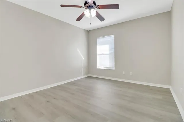 an empty room with chandelier fan and windows