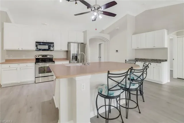 a kitchen with stainless steel appliances granite countertop a stove top oven a sink a dining table and chairs with wooden floor