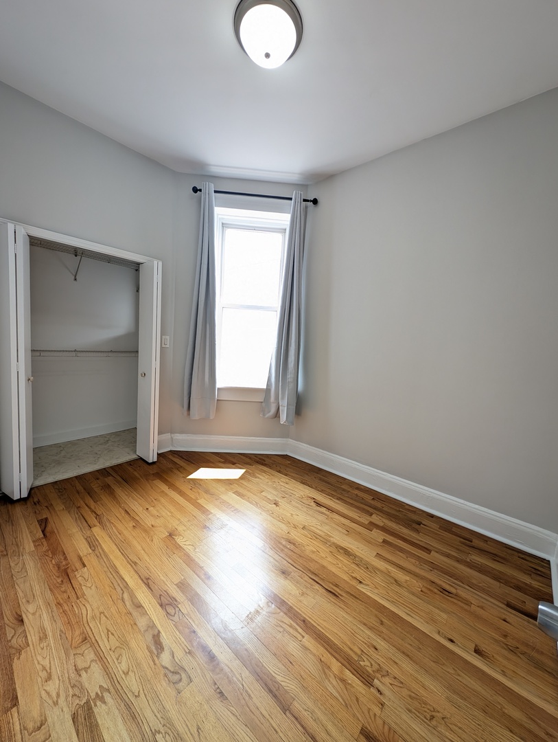 2611 West George Street, Unit 2R Chicago, IL 60618 - Photo 9 of 14 an empty room with wooden floor and windows