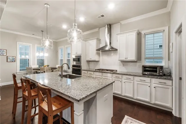a kitchen with stainless steel appliances granite countertop a stove a refrigerator a kitchen island a table and chairs
