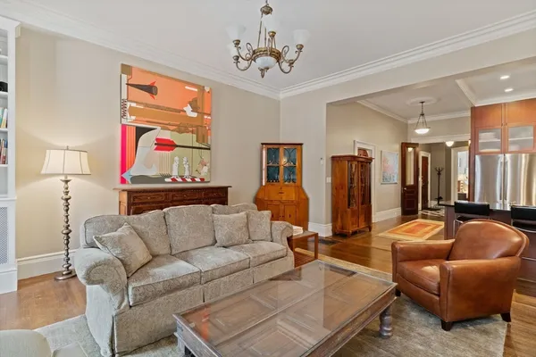 a living room with furniture kitchen view and a chandelier