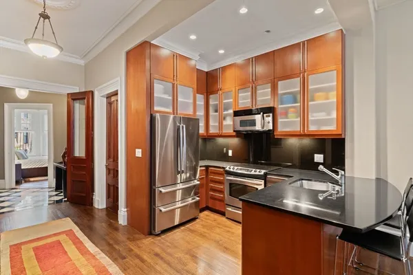 a kitchen with stainless steel appliances granite countertop a refrigerator a stove and a sink with wooden floor