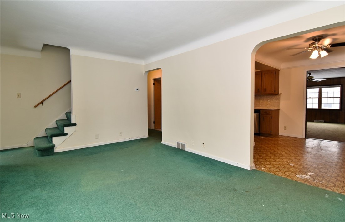 6308 Highland Road Cleveland, OH 44143 - Photo 8 of 40 Unfurnished living room featuring arched walkways, ceiling fan, carpet flooring, visible vents, and stairway