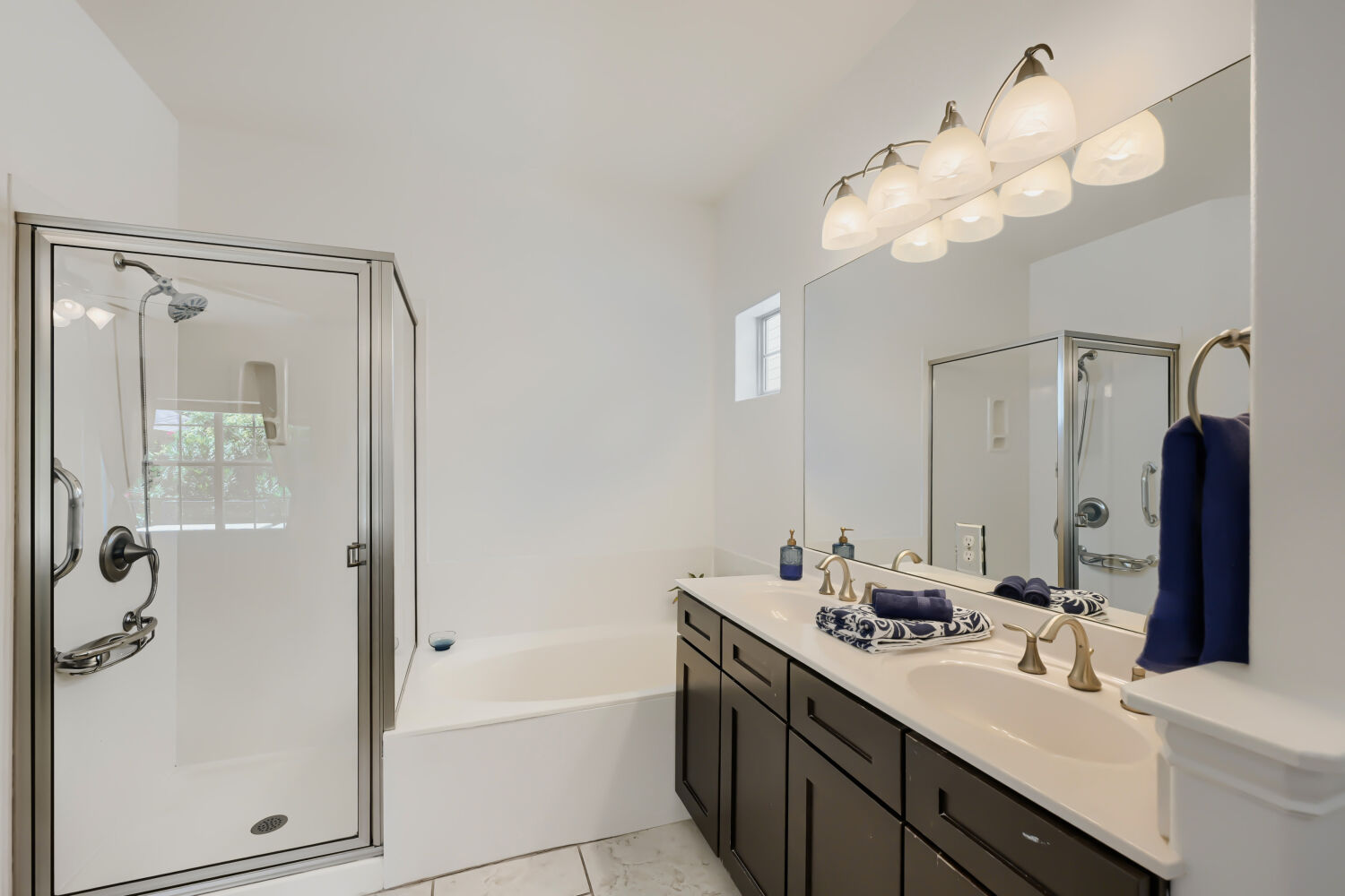 6715 Windrift Way, Unit 28 Austin, TX 78745 - Photo 14 of 19 A primary bathroom features a double vanity and a glass-enclosed shower, complemented by a large soaking tub.