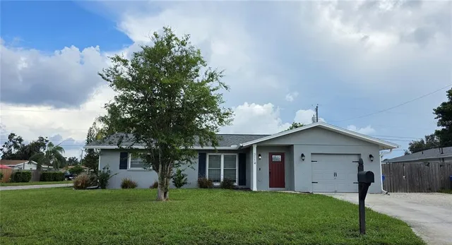 a view of a house with a yard and a large tree