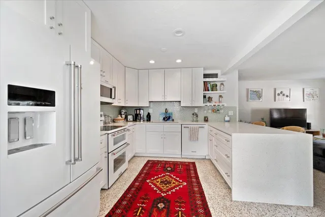 a large white kitchen with stainless steel appliances and white cabinets