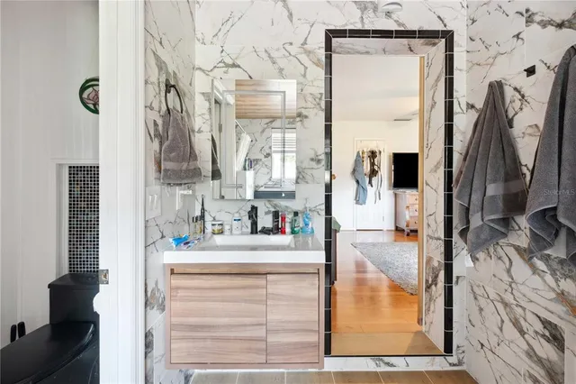 a bathroom with a sink and mirror with bathtub