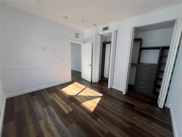 a view of an empty room with wooden floor and stairs