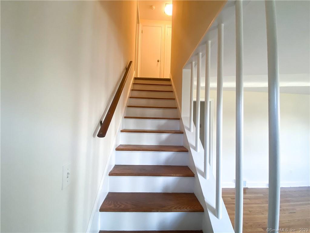 a view of staircase with wooden floor and white walls