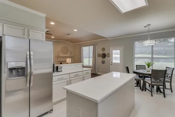 a kitchen with stainless steel appliances a refrigerator a table and chairs
