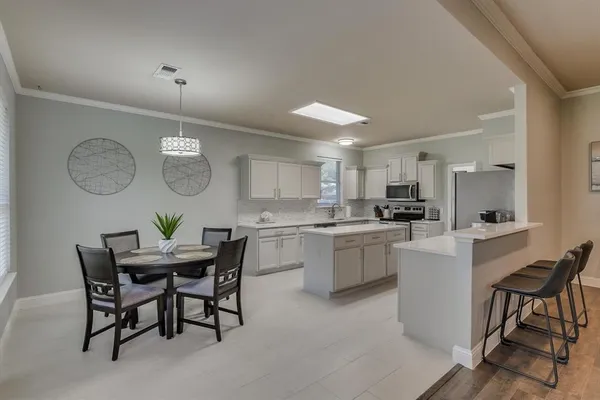 a kitchen with a table chairs a sink dishwasher and cabinets