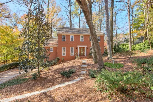 a view of a brick house next to a yard with big trees