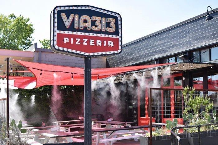 2002 East 9th Street, Unit 2 Austin, TX 78702 - Photo 30 of 32 Vibrant outdoor patio with misting system offers a refreshing dining experience under a striking sign.