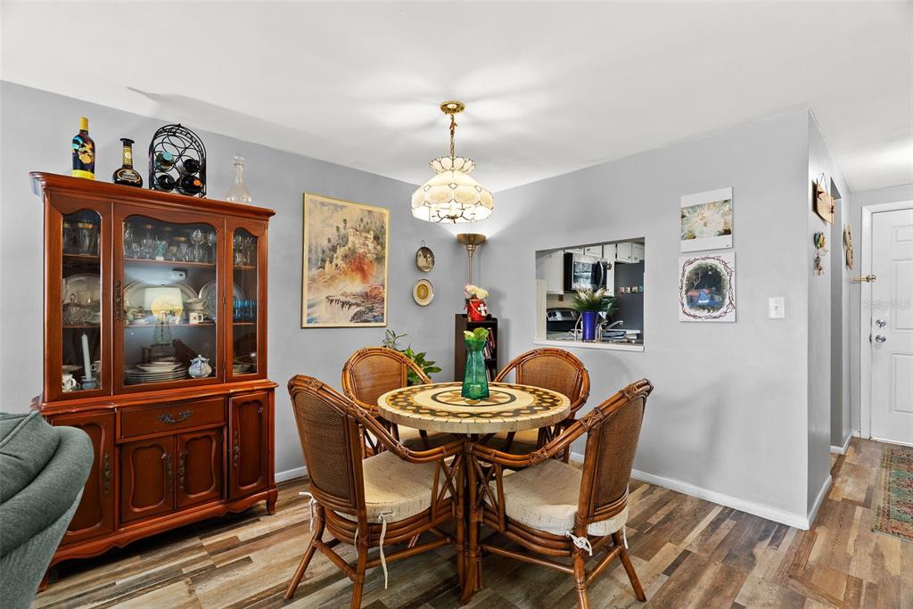 4227 Rax Place, Unit 4227 New Port Richey, FL 34652 - Photo 10 of 42 a dining room with furniture a painting a chandelier and wooden floor