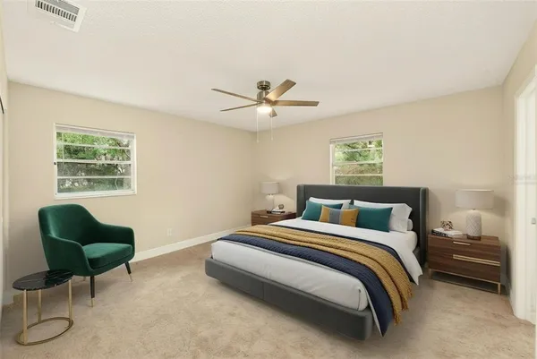 a bedroom with a bed a chair and a potted plant