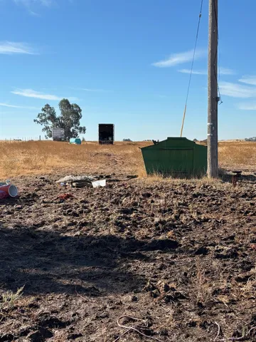 a view of a dry yard with wooden fence