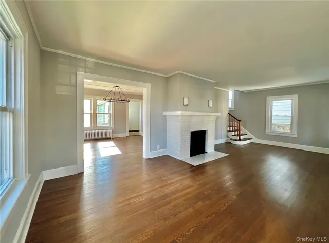 an empty room with wooden floor fireplace and windows