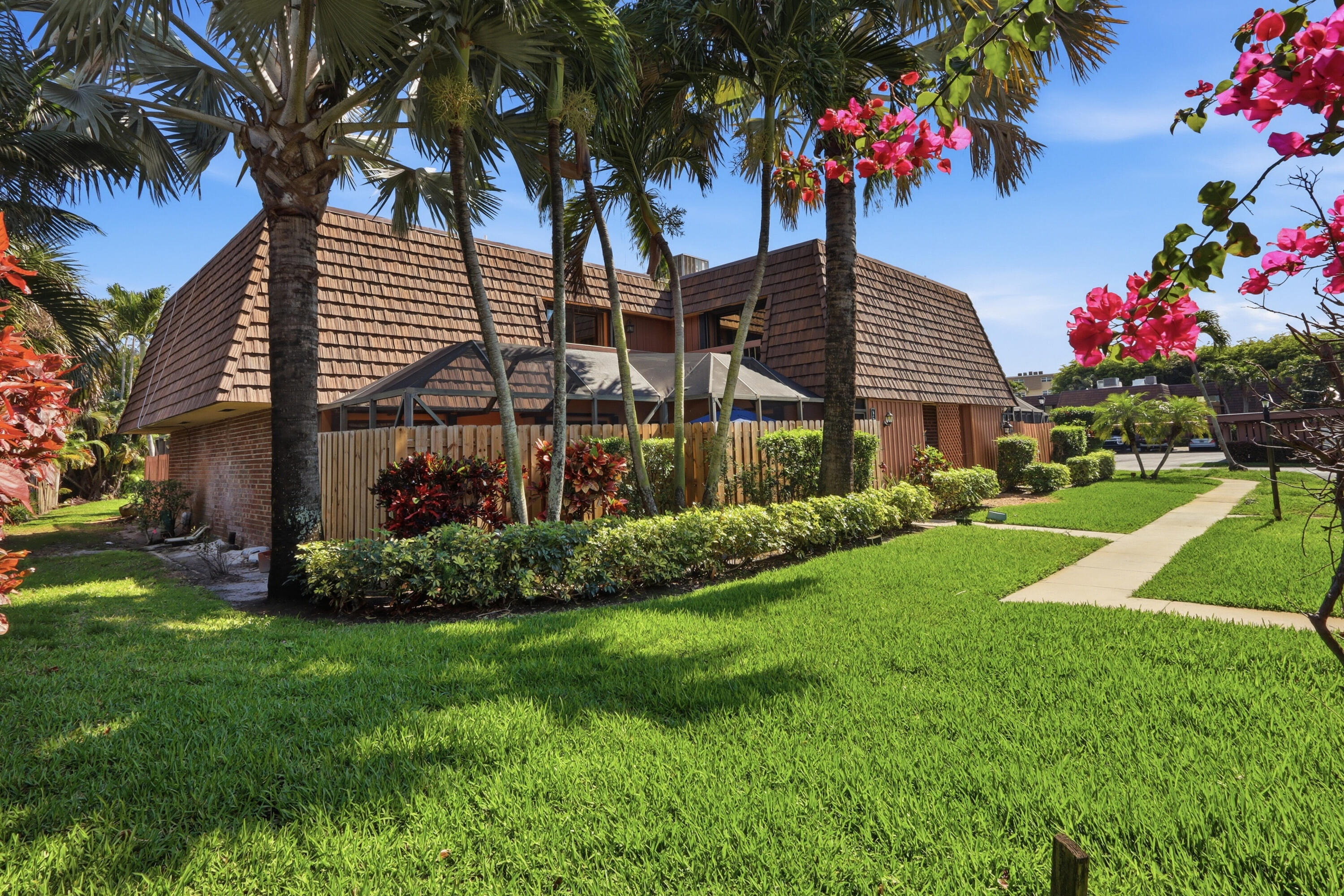 a front view of a house with a yard and palm trees