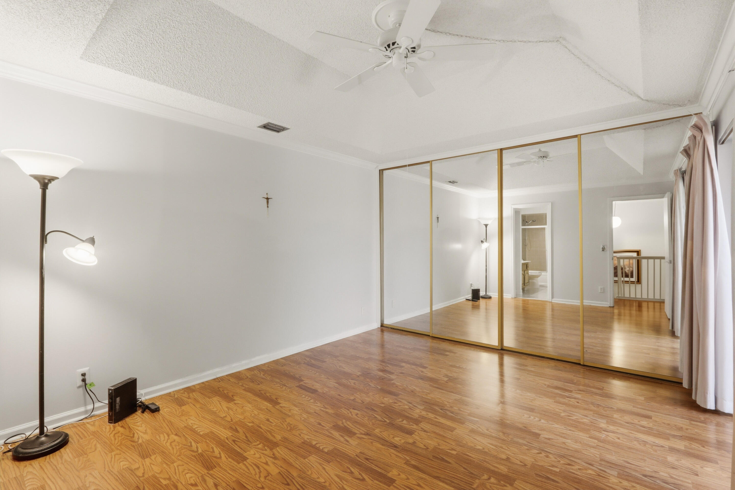 9 Atrium Circle, Unit C Atlantis, FL 33462 - Photo 27 of 54 a view of an empty room with wooden floor and a ceiling fan