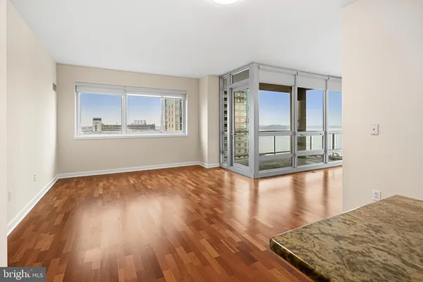 a view of empty room with wooden floor and fan