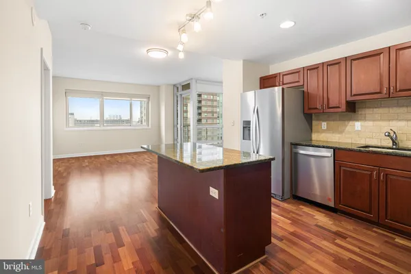 a kitchen with stainless steel appliances granite countertop a refrigerator a sink dishwasher a stove and white countertops with wooden floor