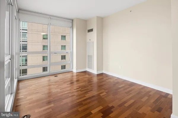 a view of an empty room with wooden floor and a window