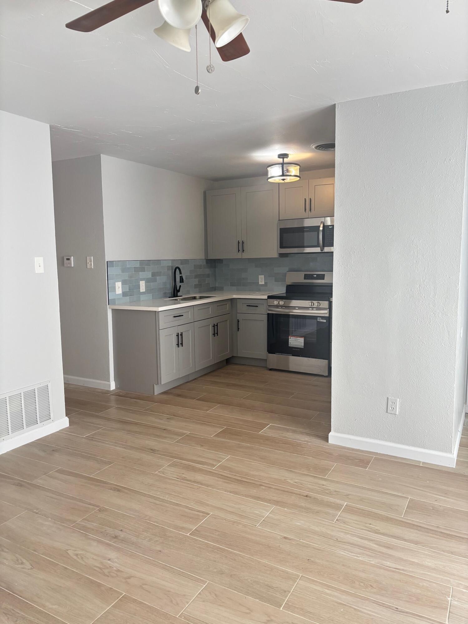2409 45th Street, Unit 8 Lubbock, TX 79412 - Photo 3 of 8 a large kitchen with kitchen island a sink dishwasher a stove and a refrigerator with wooden floor