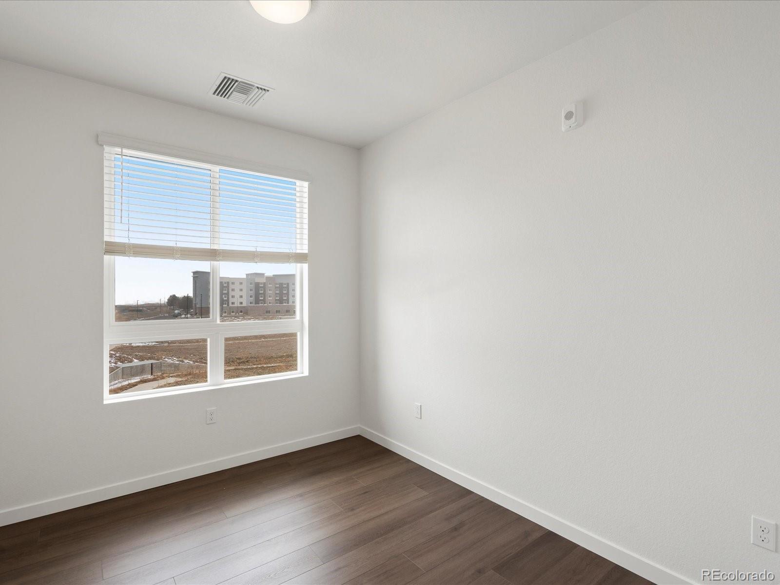 6153 North Ceylon Street, Unit 304 Denver, CO 80249 - Photo 11 of 24 an empty room with wooden floor and windows