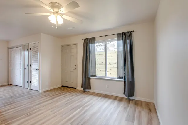 a view of an empty room with wooden floor and a window