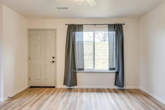 an empty room with wooden floor and windows