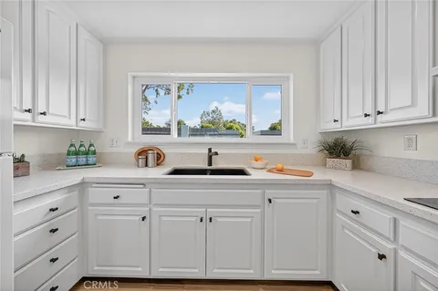 a kitchen with white cabinets and sink