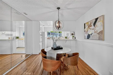 a dining room with wooden floor a chandelier a wooden table and chairs