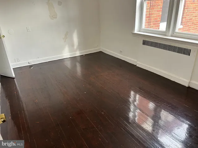 en empty room with wooden floor and windows