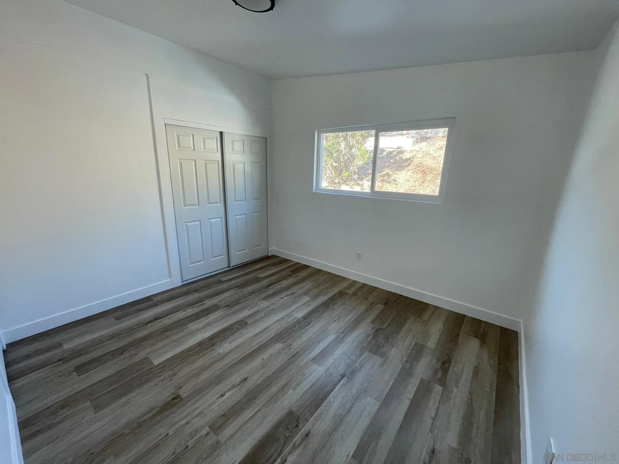 8632 Eileen Street Spring Valley, CA 91977 - Photo 8 of 12 a view of an empty room with wooden floor and a window