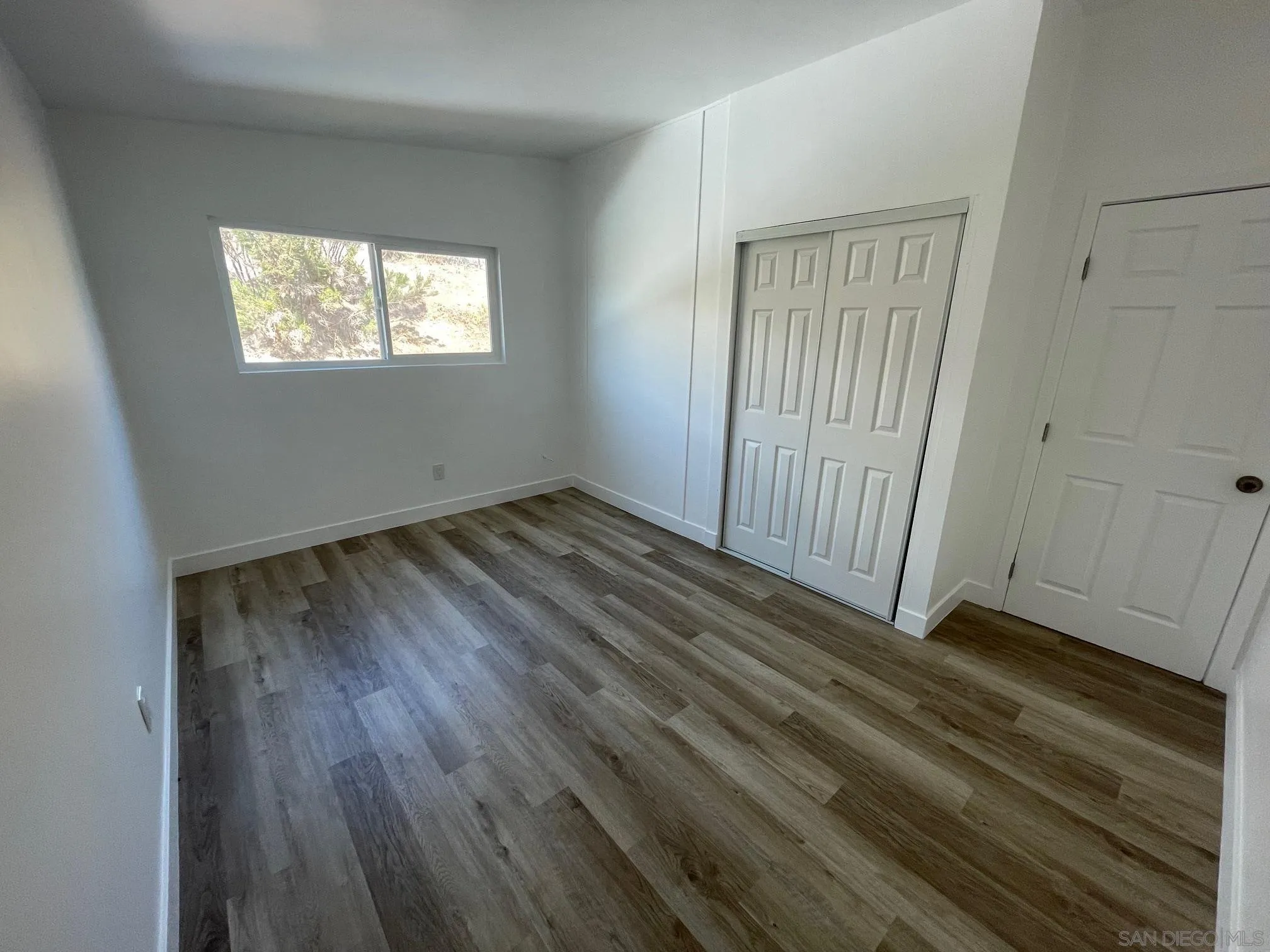 8632 Eileen Street Spring Valley, CA 91977 - Photo 9 of 12 a view of an empty room with wooden floor and a window