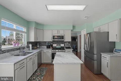 a kitchen with a sink a counter top space stainless steel appliances and cabinets