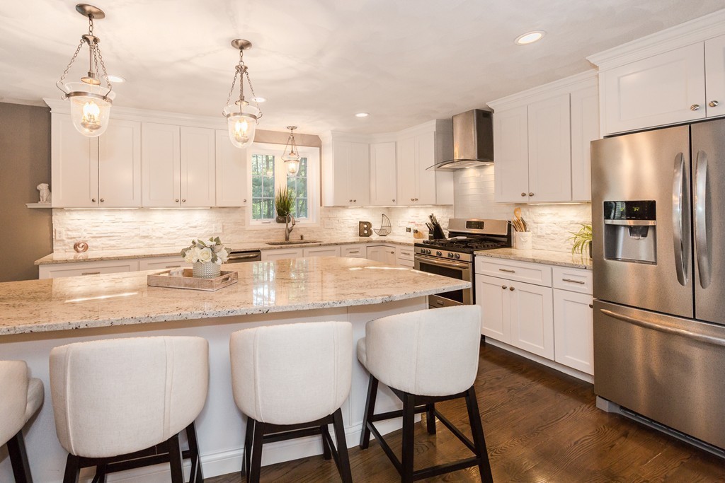 a kitchen with stainless steel appliances granite countertop a dining table chairs refrigerator sink and cabinets