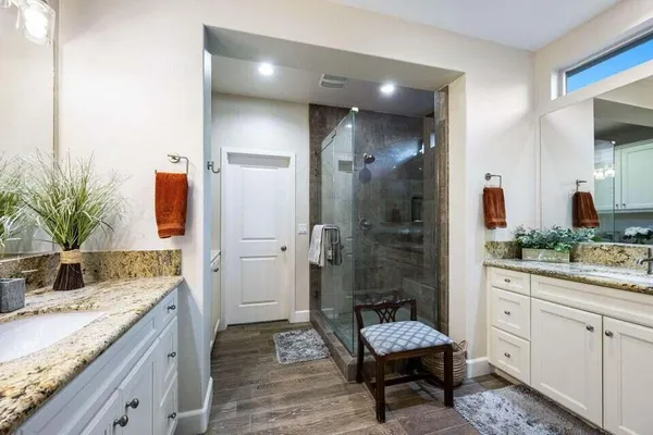 a spacious bathroom with a granite countertop sink a mirror and shower
