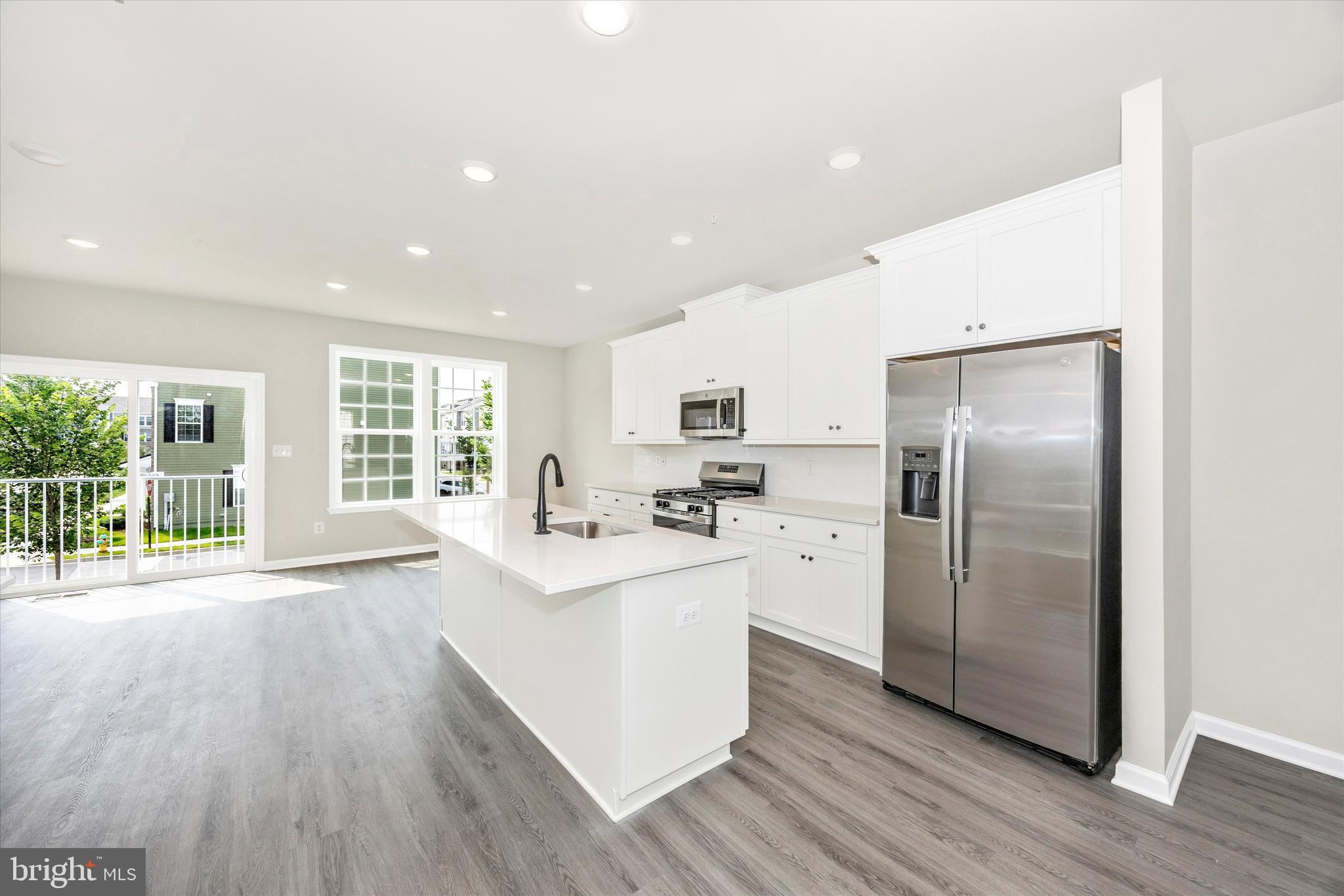 106 Spring Bank Way Frederick, MD 21701 - Photo 6 of 14 a kitchen with stainless steel appliances a refrigerator a sink dishwasher a stove and white cabinets with wooden floor next to windows
