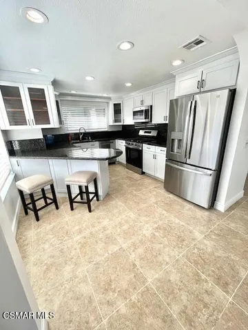 a kitchen with stainless steel appliances kitchen island granite countertop a refrigerator and a sink