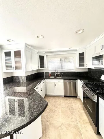 a large kitchen with granite countertop a stove and a sink