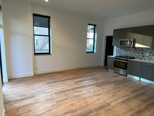 a view of kitchen and empty room with wooden floor
