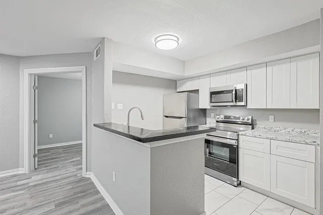 a kitchen with stainless steel appliances granite countertop a sink and dishwasher a stove top oven with wooden floor