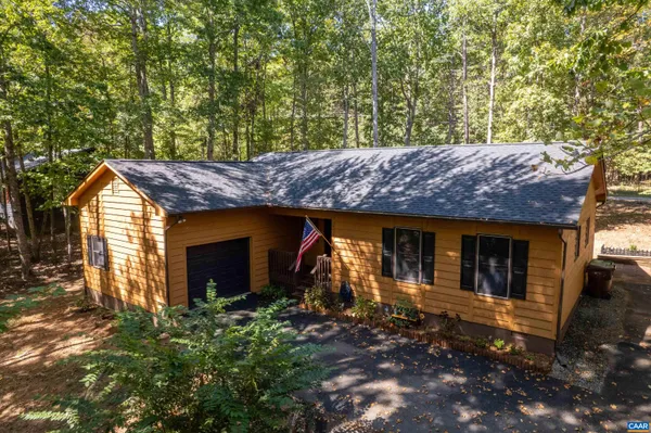 a view of a house with a small yard and large tree
