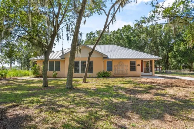 a view of a yard in front of a house with large trees