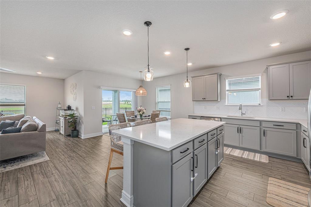 8312 Reefbay Cove Parrish, FL 34221 - Photo 11 of 36 a kitchen with kitchen island granite countertop lots of white cabinets a sink dishwasher and a stove with wooden floor