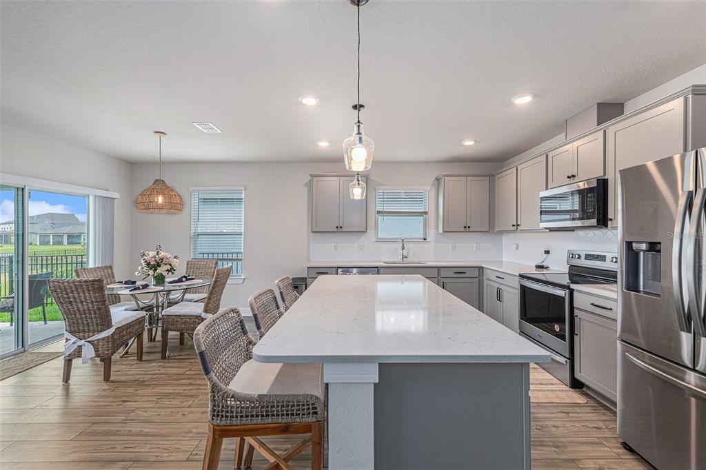 8312 Reefbay Cove Parrish, FL 34221 - Photo 12 of 36 a kitchen with kitchen island a large counter top space appliances and a dining table