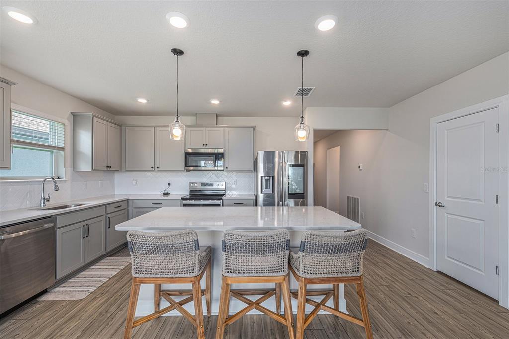 8312 Reefbay Cove Parrish, FL 34221 - Photo 9 of 36 a kitchen with refrigerator a sink and chairs