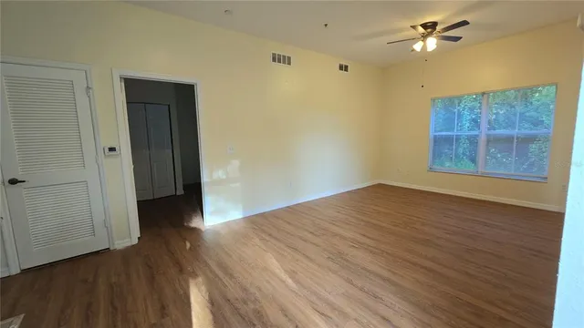a view of empty room with wooden floor and fan