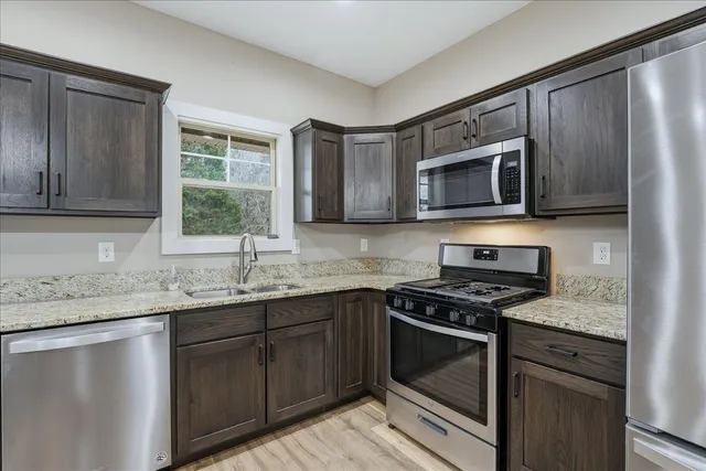 a kitchen with granite countertop cabinets stainless steel appliances a sink and a window